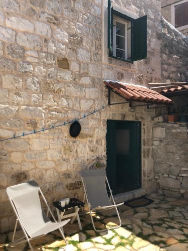 two white chairs sitting in front of a stone wall at Villa San Marco in Hvar