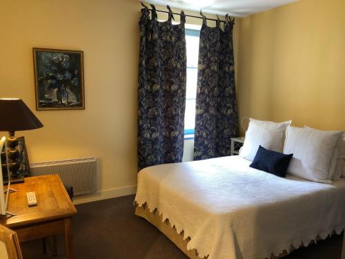 - une chambre avec un lit doté de rideaux bleus et d'une fenêtre dans l'établissement Le Moulin De La Beune, à Les Eyzies-de-Tayac