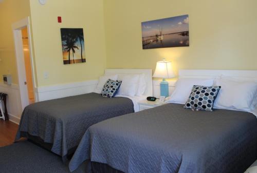 a bedroom with two beds and a table with a lamp at Topsail Shores Inn in Sneads Ferry
