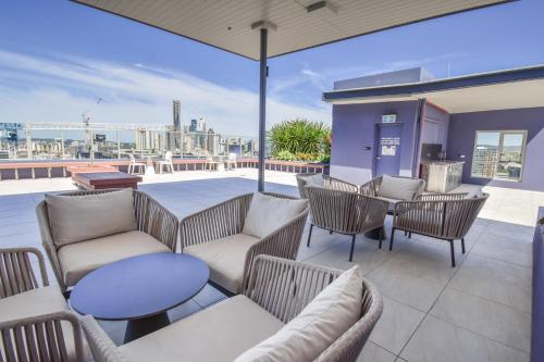 a patio area with chairs, tables, and tables with umbrellas at Belise Apartments in Brisbane