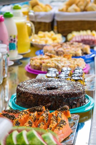 a table topped with a chocolate cake and other desserts at Pousada Casa do Rio Hostel - 8 min do Centro Hístorico in Paraty