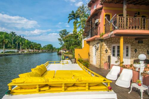 a yellow boat on a river next to a building at Pousada Casa do Rio Hostel - 8 min do Centro Hístorico in Paraty