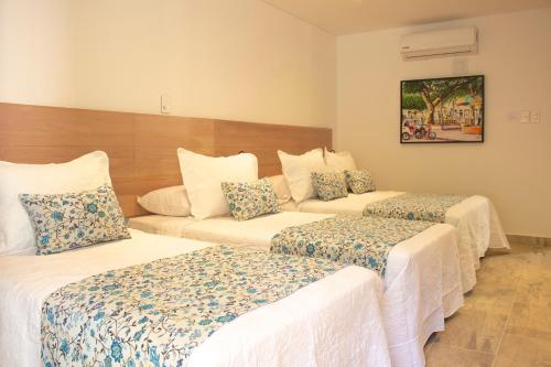 a hotel room with three beds and a couch at Hotel La Gloria in Mompos