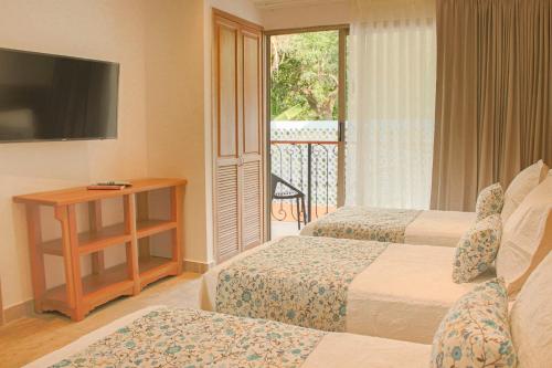 a hotel room with two beds and a balcony at Hotel La Gloria in Mompos