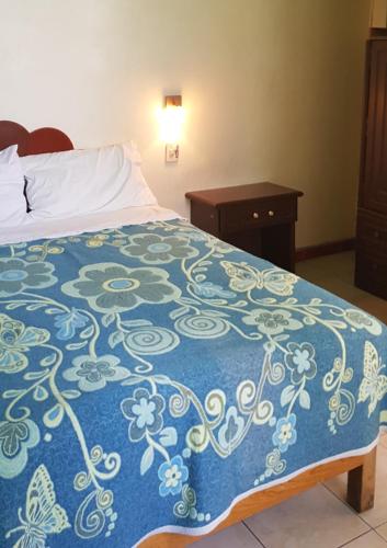 a bedroom with a bed with a blue and white bedspread at HOTEL DON JESUS (MORELOS) in Aguascalientes