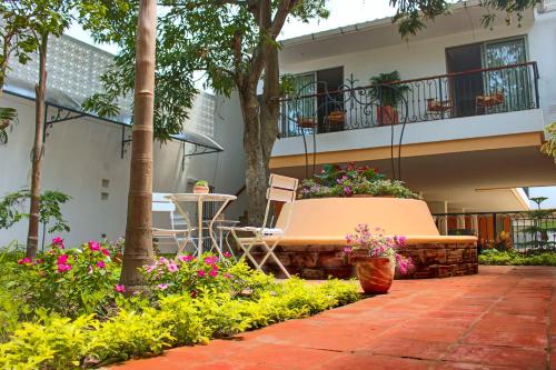 eine Terrasse mit einer Bank und Blumen vor einem Gebäude in der Unterkunft La Gloria Hotel by BespokeColombia in Mompos