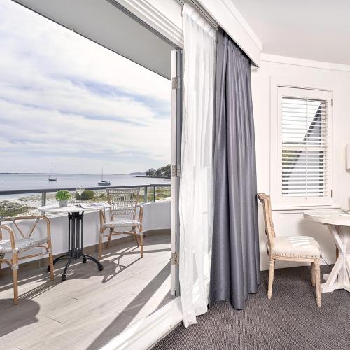 a room with a balcony with a view of the ocean at Anchorage Port Stephens in Nelson Bay