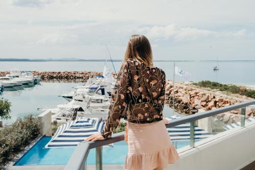 a woman standing on a balcony overlooking a marina at Anchorage Port Stephens in Nelson Bay