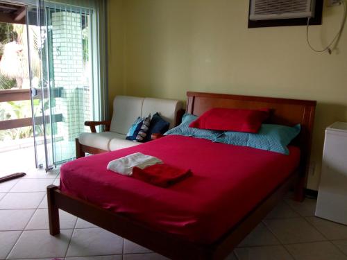 a bedroom with a bed with red sheets and a couch at Casa Baia da Babitonga in São Francisco do Sul