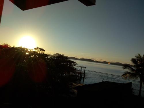 a sunset over a beach with the sun setting at Casa Baia da Babitonga in São Francisco do Sul