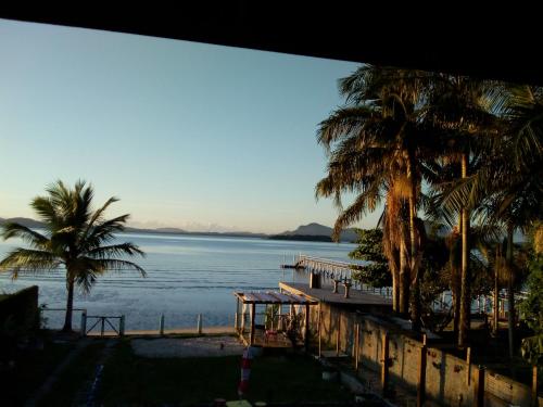a view of a beach with palm trees and the ocean at Casa Baia da Babitonga in São Francisco do Sul