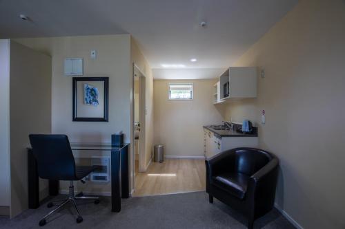 a room with a desk and two chairs and a kitchen at Abbella Lodge Motel in Christchurch