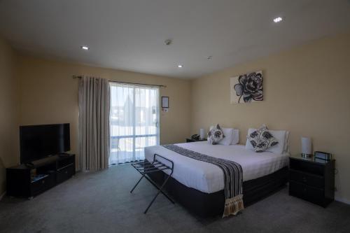 a bedroom with a bed and a flat screen tv at Abbella Lodge Motel in Christchurch
