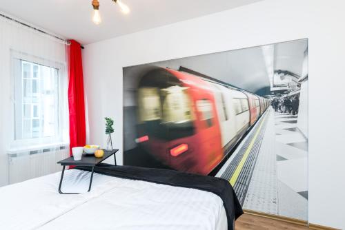 a bedroom with a painting of a train on the wall at Sleepway Apartments - Red Metro in Poznań