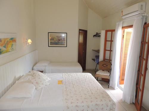 a white bedroom with two beds and a window at Recanto da Praia in Paraty