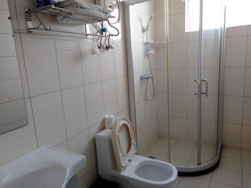 a bathroom with a shower and a toilet and a sink at Beach Garden Hotel in Dili