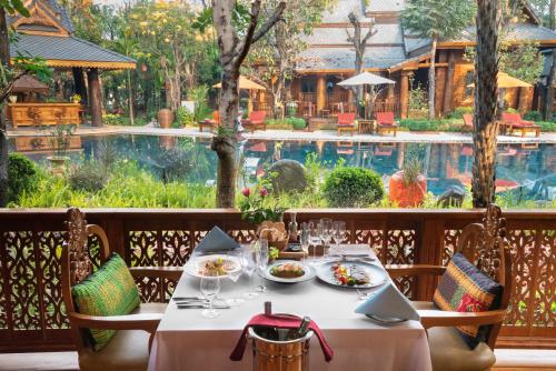 a table with plates of food at a restaurant with a pool at WandaVista Resort Khum Wang Nuea Chiang Mai清迈万达文华酒店北国之宫 in Chiang Mai