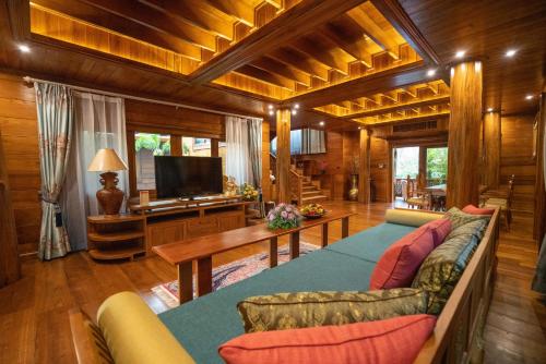 a living room with a couch and a tv at WandaVista Resort Khum Wang Nuea Chiang Mai清迈万达文华酒店北国之宫 in Chiang Mai