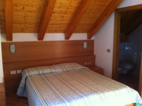 een slaapkamer met een bed in een kamer met houten plafonds bij Hotel Belfort in Spormaggiore