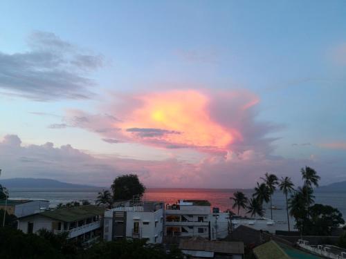 a sunset over the ocean with buildings and palm trees at Manarra Sea View Resort in Puerto Galera