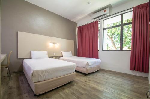a hotel room with two beds and a window at YMCA Penang in George Town
