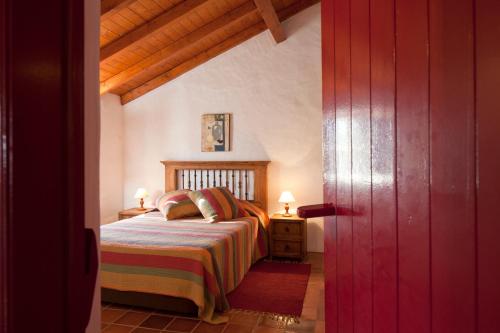 a bedroom with a bed and a red door at Monte dos Parvos in Vila Nova de Milfontes