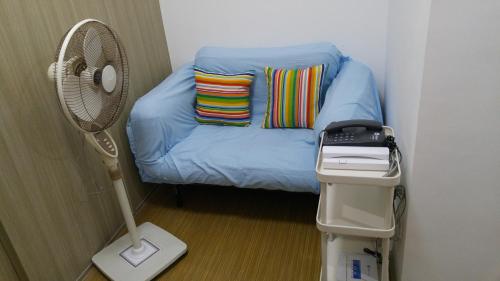 ein kleines Zimmer mit einem blauen Sofa und einem Ventilator in der Unterkunft 1BR Grace Residences w/ Internet- near BGC/McKinley in Manila