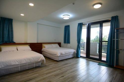 1 dormitorio con 2 camas y ventana grande en Xin Zhu Homestay, en Huxi