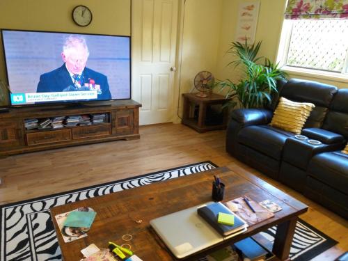 a living room with a couch and a flat screen tv at Middle Ridge, Toowoomba, in Toowoomba