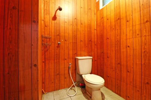 a bathroom with a toilet in a wooden wall at Wiens Residence BSD in Tangerang