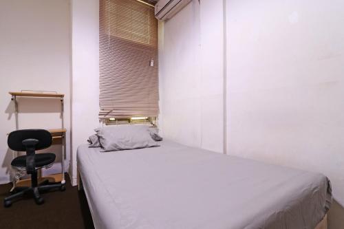 a bedroom with a bed and a chair next to a window at Wiens Residence BSD in Tangerang