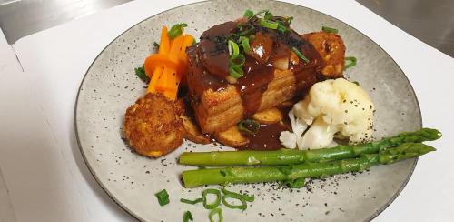 a plate of food with meat and vegetables on a table at Dampier Mermaid Hotel Karratha in Dampier