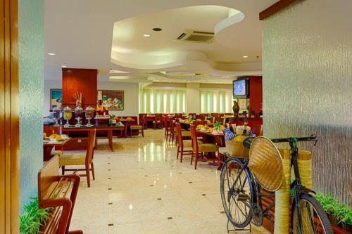a bike parked in a restaurant with tables and chairs at Hotel Sahid Surabaya in Surabaya