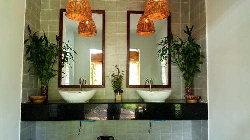 a bathroom with three sinks and three mirrors at Sahaa Beach Resort in Sihanoukville