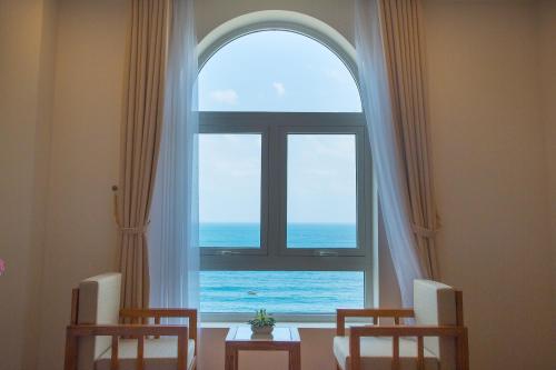 a room with a window with a view of the ocean at De Lamour Hotel in Da Nang