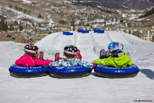 three people are sitting in an inner tube in the snow at Poste Montane Lodge by East West in Beaver Creek