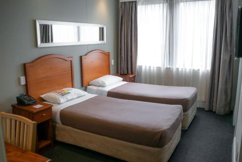雪梨的住宿－悉尼南部大酒店，酒店客房设有两张床和窗户。