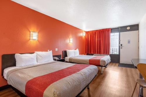 two beds in a hotel room with orange walls at Motel 6-Little Rock, AR - West in Little Rock