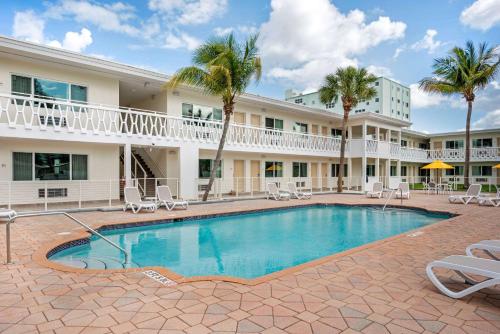 a pool in front of a hotel with chairs and palm trees at Downtown Hollywood Gardens Inn & Suites in Hollywood