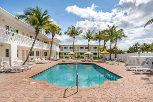 a pool with chairs and palm trees and a building at Downtown Hollywood Gardens Inn & Suites in Hollywood