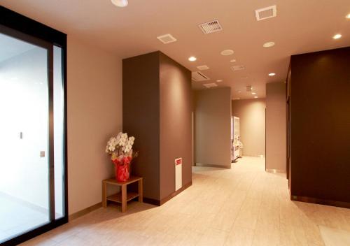 a hallway with a vase of flowers on a table at Hotel Trend Okazaki Ekimae in Okazaki