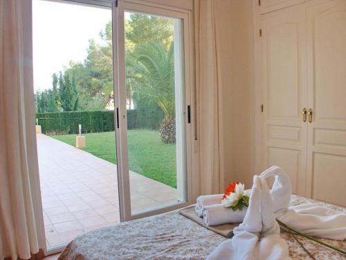 1 dormitorio con 1 cama con toallas y puerta corredera de cristal en Villa El Encanto, en Moraira