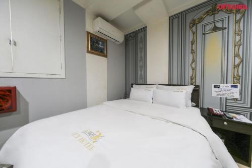 a white bed in a room with a mirror at Sky Motel in Wonju