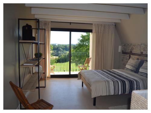 a bedroom with a bed and a view of a balcony at A L'Ombre du Tilleul in Comiac