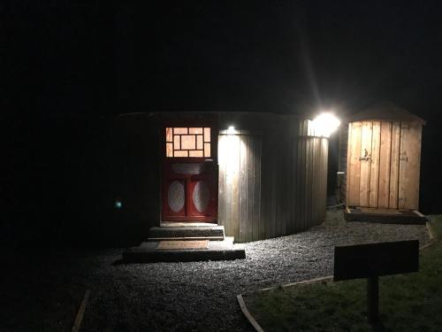 a red door and a wooden shed at night at McClure Yurt at Carrigeen Glamping in Kilkenny