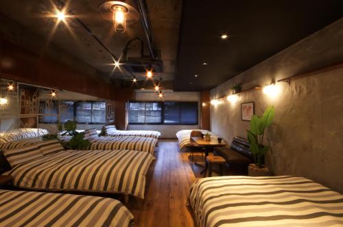 Habitación con 4 camas y mesa. en Guest House Re-worth Yabacho1 1F en Nagoya
