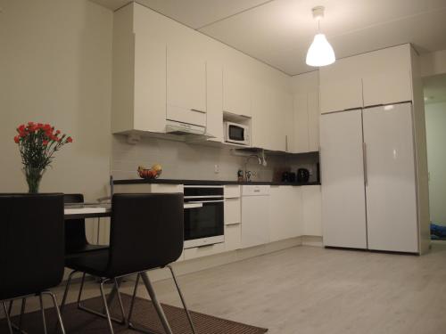 a kitchen with white cabinets and a table and chairs at Pearl in Raahe