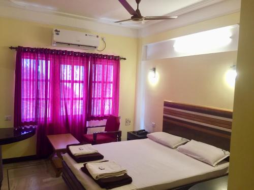 a bedroom with a large bed with pink curtains at Hotel Sun Rock in Kanyakumari