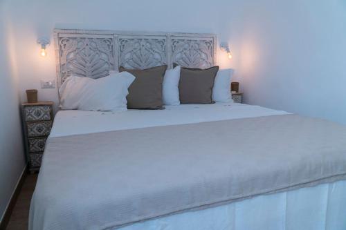 ein Bett mit weißer Bettwäsche und Kissen in einem Schlafzimmer in der Unterkunft VILLA SA PERDA COSTA REI in Costa Rei