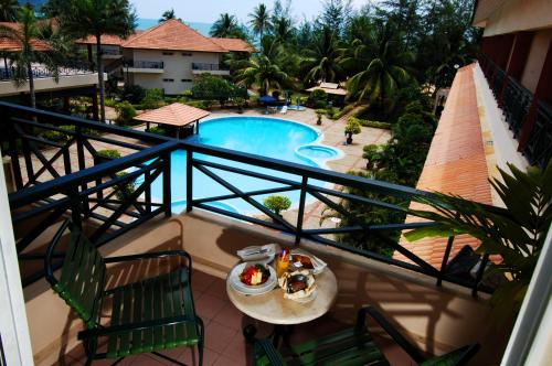 einen Balkon mit Poolblick und einen Tisch mit Speisen in der Unterkunft The Qamar Paka, Terengganu in Paka